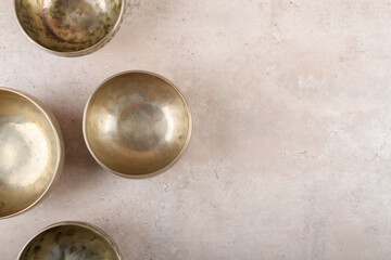 Tibetan singing bowls used during mantra meditations on beige stone background, top view, flat lay....