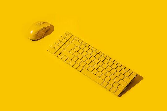Yellow wireless keyboard and yellow computer mouse on a yellow background