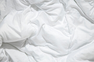 Wrinkled white blanket, an unmade bed. Top view, flat lay