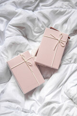 Two gift boxes on a crumpled white blanket. Top view, flat lay
