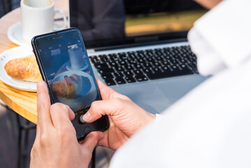 Sitting man taking pictures with his smartphone of the coffee he is drinking