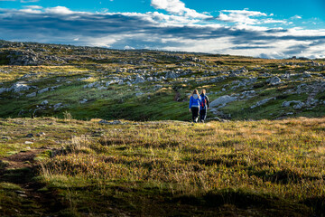 Mother and daughter on a walk across mossy tundra along the Klondike trail in Newfoundland Canada.