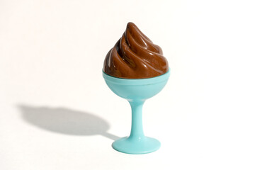 Toy chocolate ice cream in a blue bowl. White background. Top view