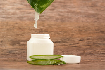 cut Aloe Vera leaf by draining into a plastic container on a wooden table