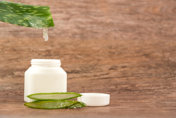 cut Aloe Vera leaf by draining into a plastic container on a wooden table