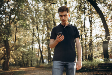 Naklejka na ściany i meble a man on a walk in the park uses a mobile phone