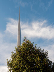 Decorated green fur tree with lights and The Spire monument in the background. Christmas time in Dublin city, the capital of Ireland. Festive season celebration.