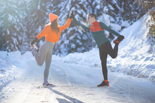 Female and male runner doing exercise at winter time