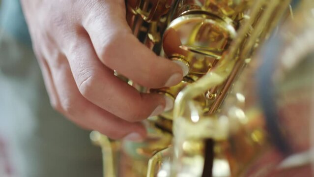Close up shot of hand of unrecognizable man pressing keys of saxophone while playing music