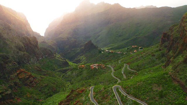 Beautiful aerial view of colorful dayglow green landscape in Masca Gorge and small mountain village in ravine during sunrise. Magical glow of rock tops. Tenerife Canary Islands Spain Europe.