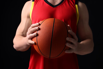 Athletic man with basketball ball on black background, closeup