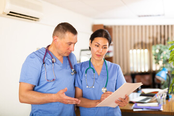 Two professional doctors checking the patient papers in a doctor office in clinic