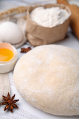 Fresh dough and ingredients on white wooden table, closeup