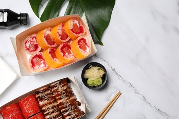 Food delivery. Delicious sushi rolls served on white marble table, flat lay with space for text