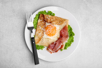 Delicious crepe with egg served on light gray table, flat lay. Breton galette