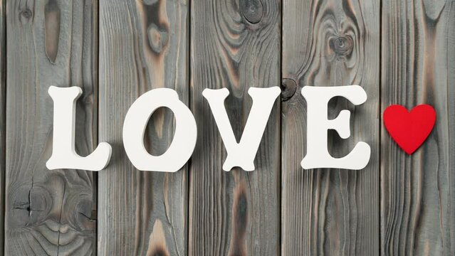 White plastic letters moving from the right side, forming word love, heart appearing and giving knock to E letter. Love and care fore st Valentines day, 8 march or mother day. Stop motion video, 4k