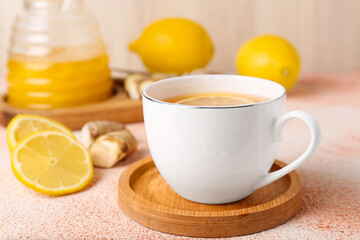 Tea, honey, lemon and ginger on beige textured table, closeup