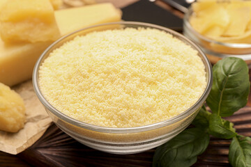 Delicious grated parmesan cheese in bowl on wooden table, closeup