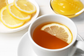 Cup with delicious immunity boosting tea, lemon and honey on white wooden table, closeup