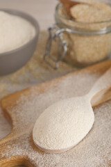 Spoon with quinoa flour on wooden table, closeup
