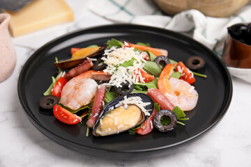 Plate of delicious salad with seafood on white marble table, closeup