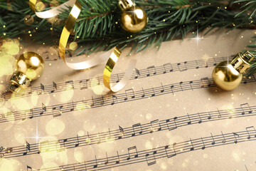 Fir branches and golden balls on Christmas music sheets, above view. Bokeh effect