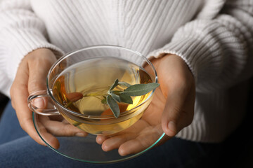Woman drinking tasty herbal tea, closeup view