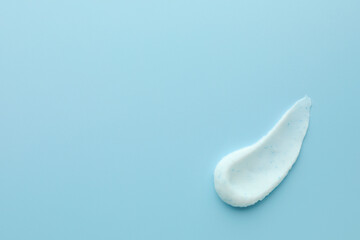 Sample of face scrub on light blue background, top view. Space for text