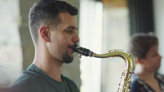 Tilt up shot of musician playing saxophone while having studio rehearsal with band