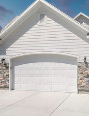 Vertical Puffy clouds at sunset Three car garage exterior with two white garage doors with arche