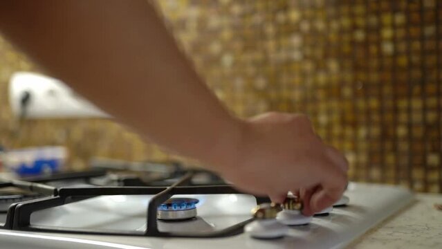 close-up, a man's hand turns on a gas stove and puts a raiser coffee maker