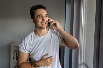 One man caucasian male standing by the window using mobile phone talk
