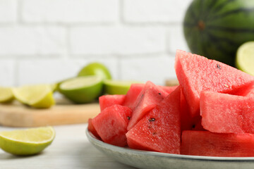 Slices of delicious watermelon and limes on white wooden table, closeup. Space for text
