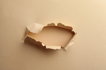 Hole in light beige paper on color background