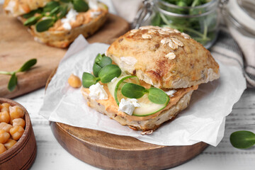 Delicious sandwich with hummus and ingredients on white wooden table