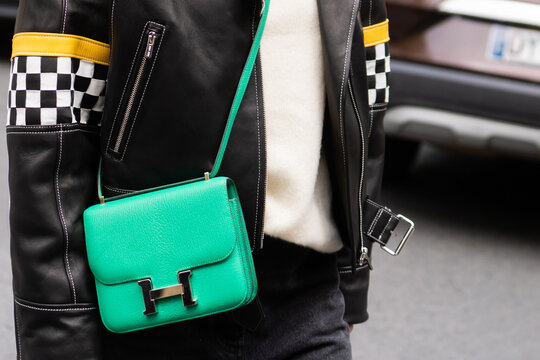 Paris, France - October, 1, 2022: woman wearing Constance green leather bag from Hermes, street style outfit details.