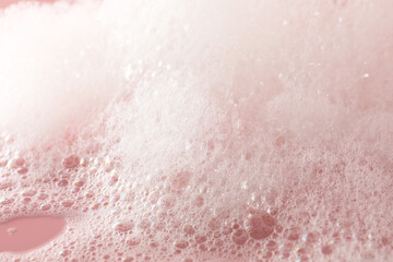 Fluffy bath foam on pink background, closeup