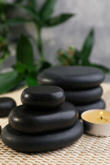 Stacked spa stones, bamboo and candle on wicker mat
