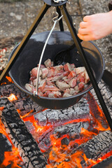 Meat in a cauldron.food on the fire.Cooking outdoors and on the go.Camping cooking.Wood fire and cauldron with food.street food