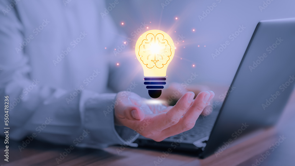 Poster man holding a abstract light bulb while working on the computer to think and create new ideas with t