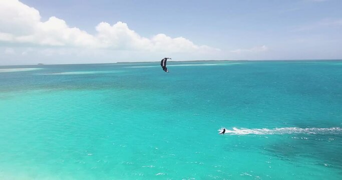 Aerial tracking shot man kitesurf in the middle of nowhere, blue ocean