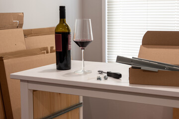 wine bottle and glass on wooden shelf, furniture assembly, moving in a new house