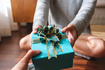Closeup image of a couple people giving and receiving a gift box to each other