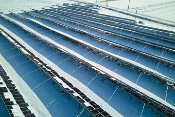 Aerial view of snow melting from covered solar photovoltaic panels at sustainable electric power plant for producing clean electrical energy. Low effectivity of renewable electricity in winter