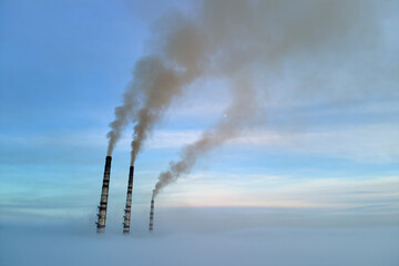 Coal power plant high pipes with black smoke moving upwards polluting atmosphere. Production of electrical energy with fossil fuel concept