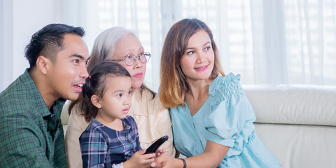 Three generation family watching television at home