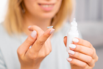 Woman holding contact lens on the finger and eye drop in her hand. Eyecare concept. 