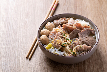 Rice noodles soup with pork in bowl on wooden background, Asian food