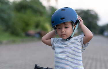 Fototapeta na wymiar Little kid Boy adjusting bike helmet