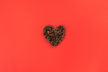 Coffee beans forming heart shape on red studio background. Charity and donation on holidays. I give you all my heart. Falling in love and confession on saint valentines day. Flat lay, copy space